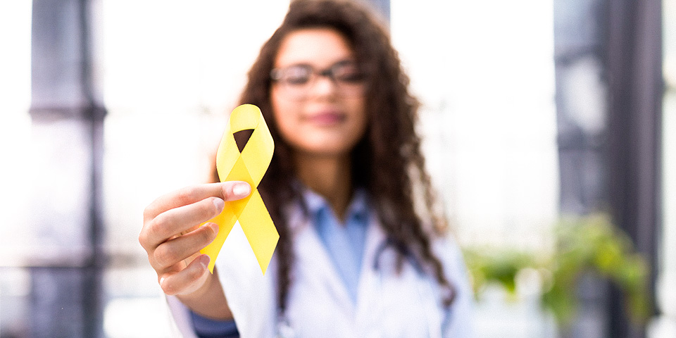 Image of a female medical staff member holding up a yellow ribbon.
