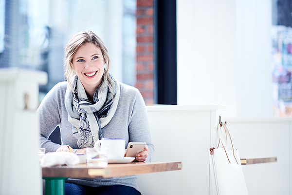 Woman at a booth with coffee and her smartphone