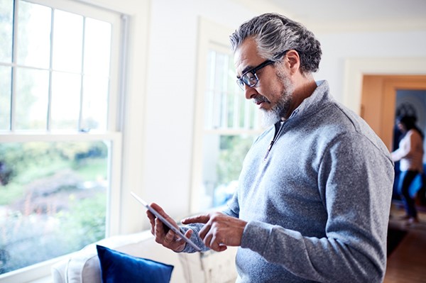 Older male views information on his smart phone in an indoor setting