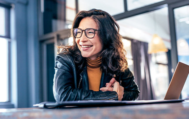 Woman using her laptop looks off camera smiling