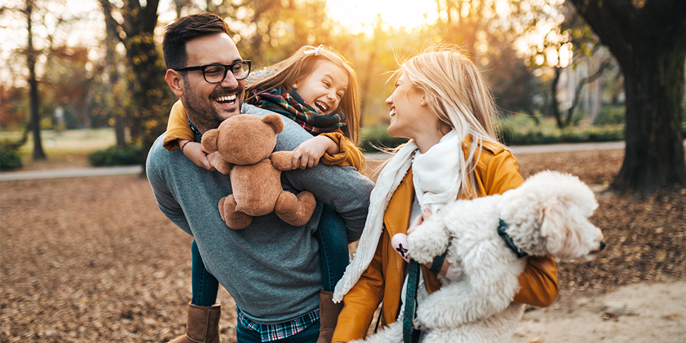 Adult male and female with a young girl and dog in an outdoor park setting