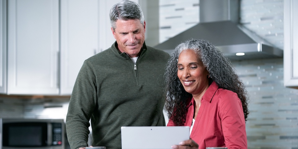Man and woman looking at laptop in kitchen