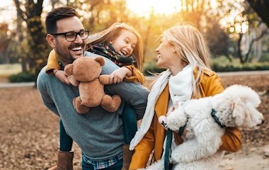 Adult male and female with a young girl and dog in an outdoor park setting
